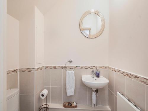 a white bathroom with a sink and a mirror at Harbour Retreat in Garlieston