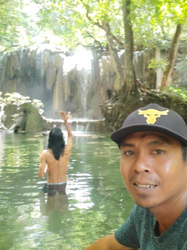 a man in a hat in the water near a waterfall at Boneputeh Homestay in Taliwang