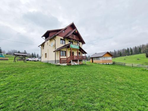a house on a grassy field in a field at Cabana Poiana Dealul Frumos in Gîrda de Sus