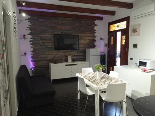 een woonkamer met een tafel en een tv aan een bakstenen muur bij Casa Balestrate in Balestrate