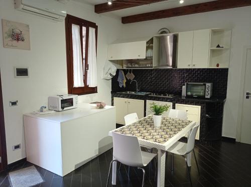 een keuken met een tafel en witte kasten en een tafel en stoelen bij Casa Balestrate in Balestrate