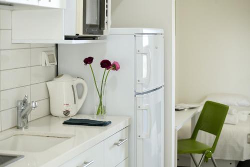 a kitchen with a white refrigerator and flowers in a vase at דירות גני תערוכה - TLV university apartments near Expo by Sea N' Rent in Tel Aviv