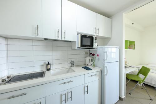 a white kitchen with a sink and a refrigerator at דירות גני תערוכה - TLV university apartments near Expo by Sea N' Rent in Tel Aviv