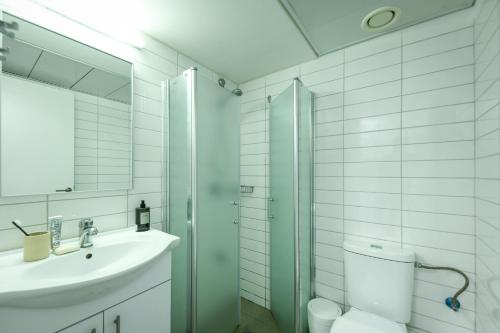a white bathroom with a sink and a shower at דירות גני תערוכה - TLV university apartments near Expo by Sea N' Rent in Tel Aviv