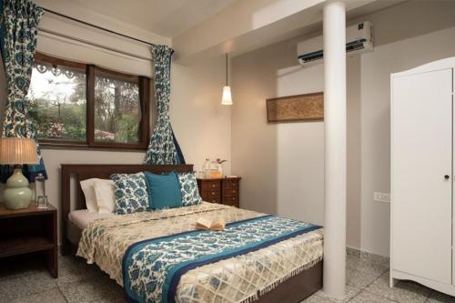 a bedroom with a bed with blue and white pillows at ama stays & trails - Dulwich Park View in Panchgani