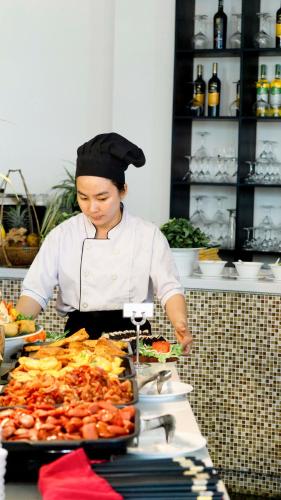 a woman in a kitchen preparing food on a table at Seaside Boutique Resort Quy Nhon in Quy Nhon