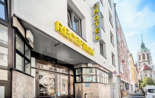 un edificio con una señal amarilla en el costado. en B&B Hotel München-Hbf en Múnich