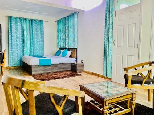 a bedroom with a bed with blue curtains and a table at Staynest Mashobra with balcony- A peacefull stay in Shimla