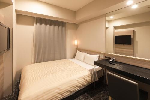 a hotel room with a bed and a mirror at Sotetsu Fresa Inn Shimbashi Hibiyaguchi in Tokyo