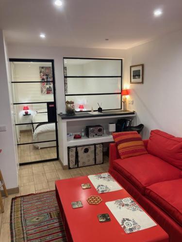 sala de estar con sofá rojo y chimenea en SUITE AVEC TERRASSE ET JARDIN AUX PORTES DE PARIS, en Les Pavillons-sous-Bois
