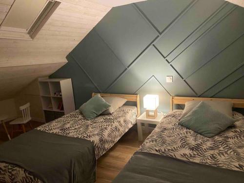 une chambre avec deux lits et un mur bleu dans l'établissement La maison près du port, à Fécamp