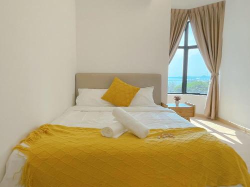 a bed with a yellow blanket and a window at Mutiara Melaka Beach Resort by Minso in Tangga Batu