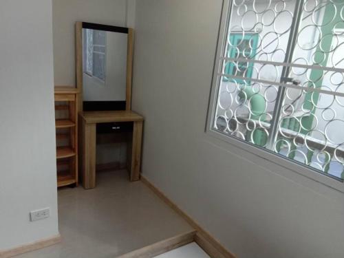 Zimmer mit einem Fenster, einem Schreibtisch und einem Spiegel in der Unterkunft 229 White House in Ban Khlong Yuan