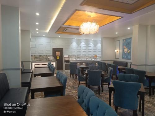 a restaurant with tables and chairs and a chandelier at Tulip Tree Hotel in Katra