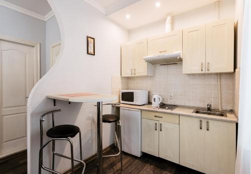 uma pequena cozinha com armários brancos e uma mesa e bancos em Апартаменты в центре Киева на Бессарабской Площади 7 em Kiev