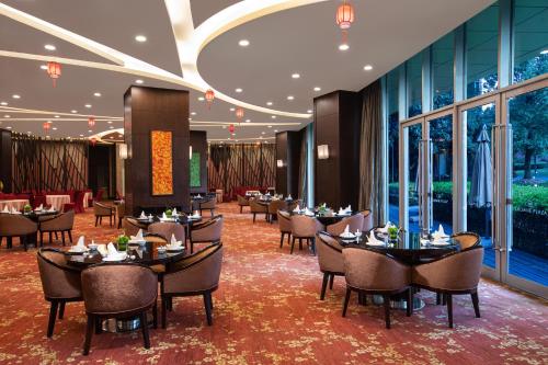 Crowne Plaza Shanghai Xiayang Lake, an IHG Hotel في Qingpu: غرفة طعام مع طاولات وكراسي ونوافذ