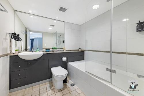Un baño con lavabo, inodoro y espejo. en KozyGuru | Haymarket | 2B Apt With Amazing View | Walk To Darling Harbour, en Sídney