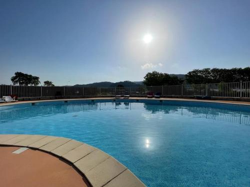 une grande piscine bleue avec le soleil en arrière-plan dans l'établissement La Petite Poule Rousse - Maison avec piscine, à Anduze
