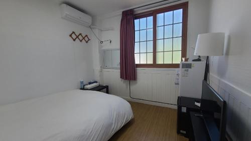 a white bedroom with a bed and a window at Bella Yuna Inn in Jeju