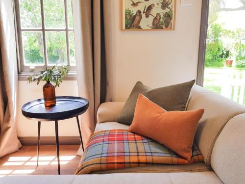a living room with a couch with pillows and a table at Clonmara Country House and Cottages in Port Fairy