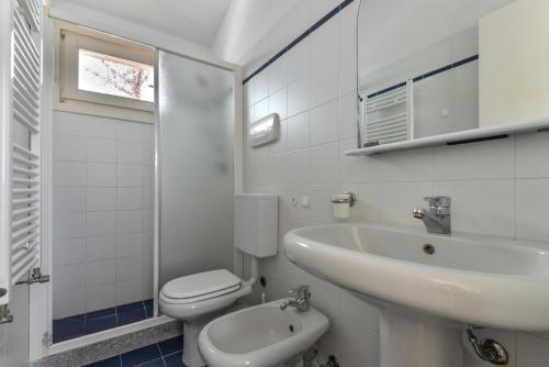 Un baño blanco con lavabo e inodoro. en Appartamento La Spiga, en Procchio