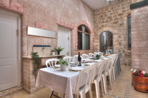 a dining room with a long table and white chairs at בראשית - סוויטות בוטיק בצפת העתיקה - Beresheet - Boutique Suites in the Old City in Safed
