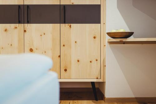 a kitchen with wooden cabinets with a bowl on a shelf at Hotel Schmuckhof in Chiusa