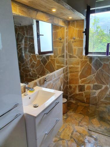 a bathroom with a sink and a stone wall at Willa wakacyjna z basenem w Eretria in Eretria