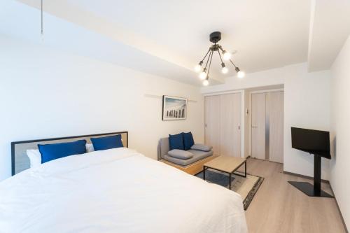um quarto com uma cama branca e uma televisão em Casa Blan em Tóquio