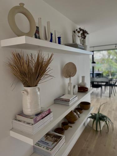 a white shelf with books and a vase with a plant at Chez Arthur in Marche-en-Famenne