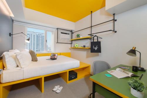 Habitación pequeña con cama, escritorio y mesa. en lyf Malate Manila - Managed by The Ascott Limited, en Manila