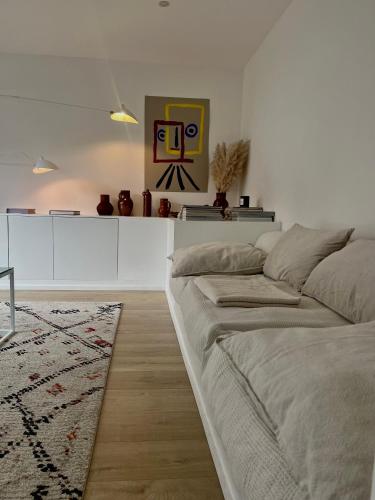 a white living room with a bed and a rug at Chez Arthur in Marche-en-Famenne