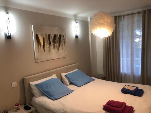 um quarto com uma cama com almofadas azuis e um lustre em Appart Nice Marguerite em Nice