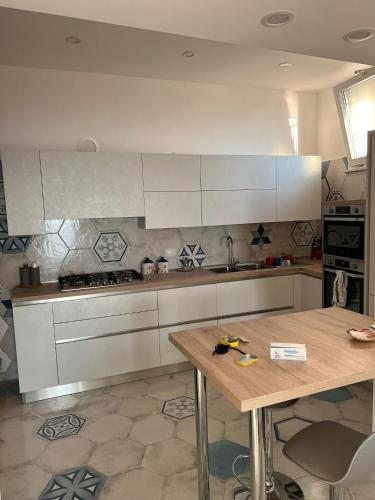 een keuken met witte kasten en een houten tafel bij Coralinehaven in Castellammare di Stabia