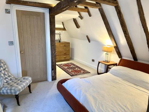 a bedroom with a bed and a chair and a door at Petworth Cottage-Sleeps 6-Pet Friendly-Central in Petworth