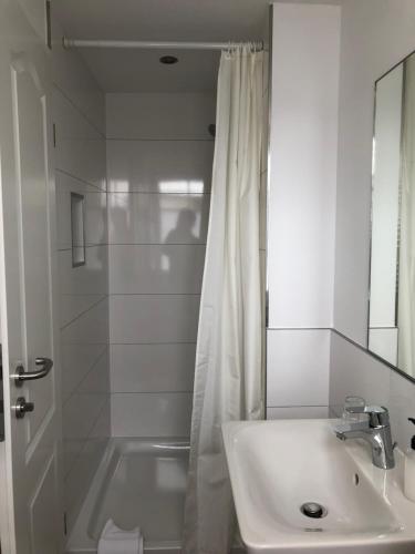 a white bathroom with a sink and a shower at Pension "Strandhotel" in Vitte