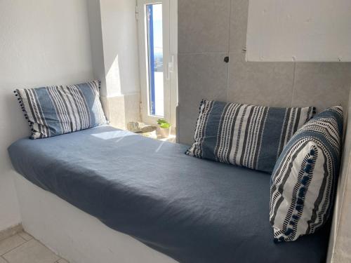 a bed with blue sheets and pillows in a room at Sea Esta Serifos Stylish Family Home, Sea View in Serifos Chora