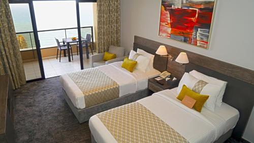 a hotel room with two beds and a balcony at La Vida Suite in Beirut