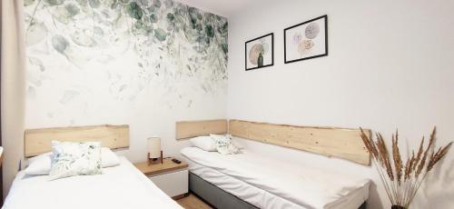 two beds in a room with white walls at Zielona Noc in Polanica-Zdrój