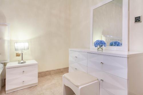 a white bathroom with a white dresser and a mirror at Bespoke Holiday Homes - Palm Jumeirah- 1 Bedroom Fairmont North Residence in Dubai