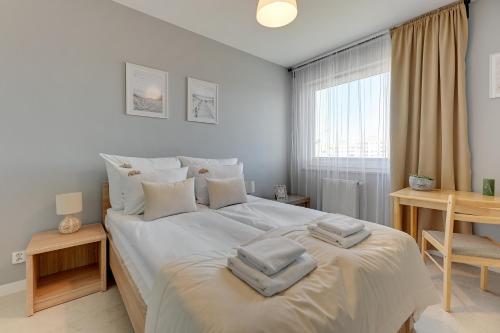 a bedroom with a large white bed with towels on it at Downtown Apartments Seaside Awiator in Gdańsk