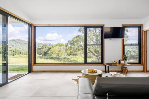 a living room with a couch and large windows at Gan Eden Retreat-Byron bay , luxuries escape in Mullumbimby
