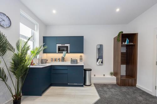 a kitchen with blue cabinets and a sink and a clock at Morecambe Bay Studio Apartments Free Parking By Beach Front in Morecambe