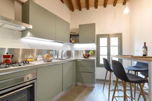 a kitchen with white cabinets and bar stools at Albergo Diffuso Borgo Santo in Asciano