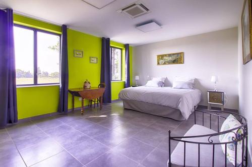 Schlafzimmer mit grünen Wänden, einem Bett und einem Schreibtisch in der Unterkunft La maison des Eucalyptus - Piscine, jacuzzis et lac in Orange