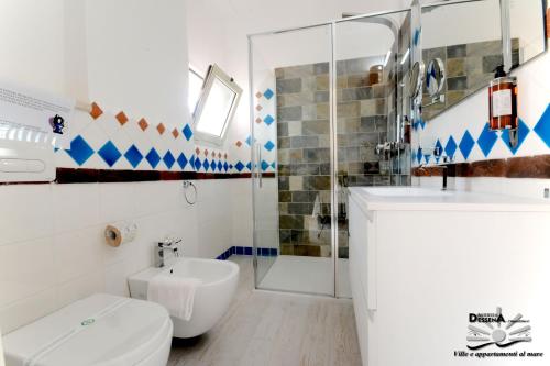 La salle de bains est pourvue de toilettes, d'un lavabo et d'une douche. dans l'établissement Villa Dessena Bed and Breakfast, à Cala Liberotto