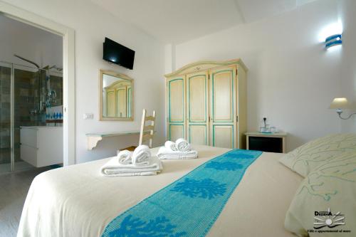 1 dormitorio con 1 cama grande y toallas. en Villa Dessena Bed and Breakfast en Cala Liberotto