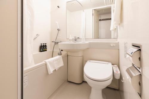 a white bathroom with a toilet and a sink at Sotetsu Fresa Inn Shimbashi Hibiyaguchi in Tokyo