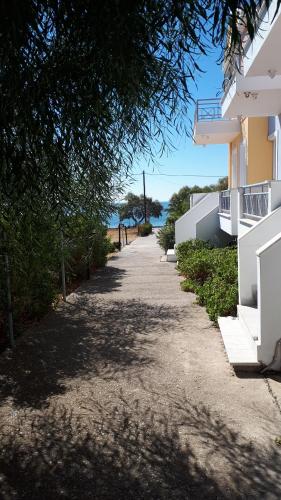 a sidewalk next to a building next to the ocean at Argo Apartments in Vatera