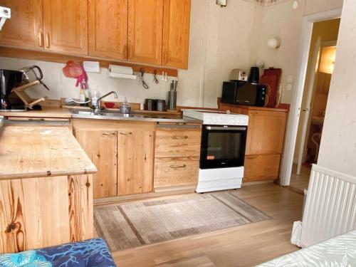 cocina con armarios de madera y horno de fogón blanco en Cottage with sea view, Kattviksvägen, en Båstad